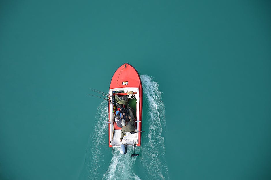 pexels-photo-240561-240561 Top view of a red motorboat with fishermen navigating open turquoise waters.